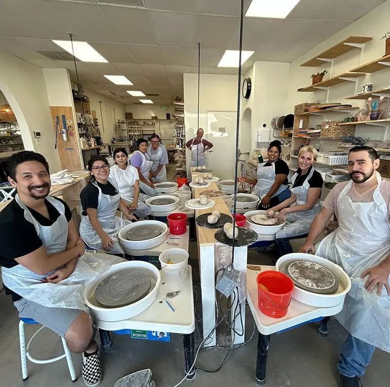 Five members of the 360 Media Direct team smiling together at a pottery studio.