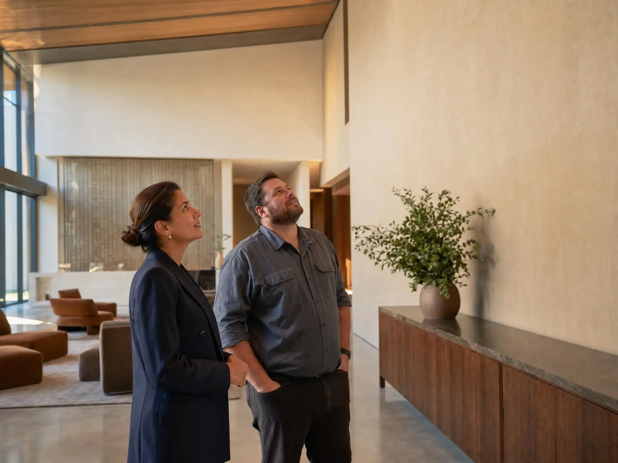A hotel operations manager and a maintenance technician looking over a lobby wall together.