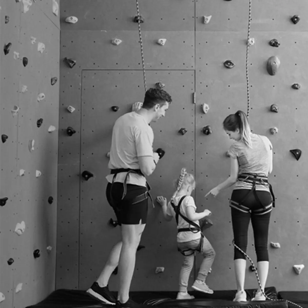 A family climbing an indoor bouldering wall together, the kind of outing CertifiKID sells deals on.